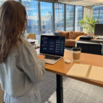 Woman working at kitchen table with AI chat interface on laptop
