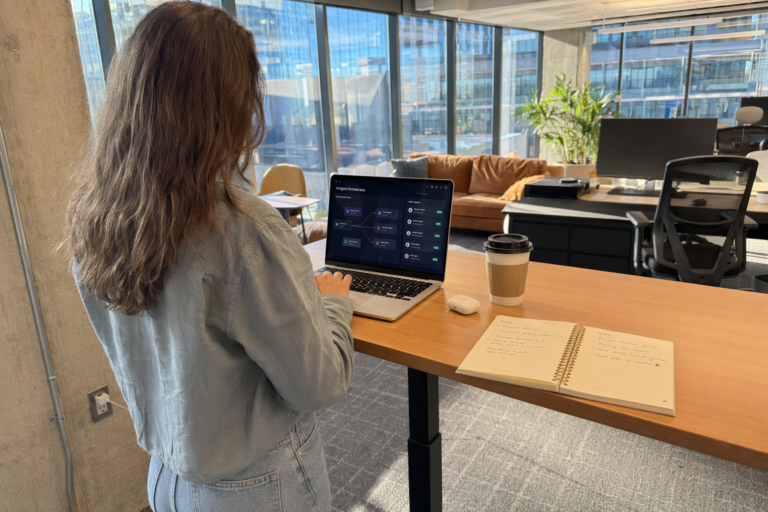 Woman working at kitchen table with AI chat interface on laptop