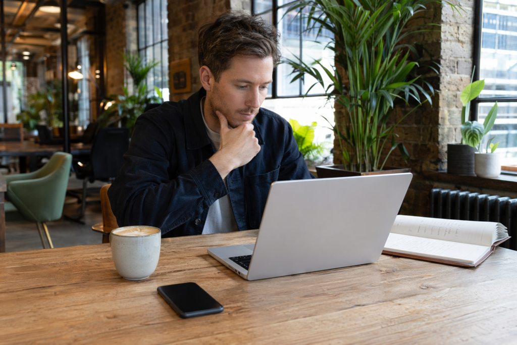 Woman working at kitchen table with AI chat interface on laptop