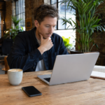 Woman working at kitchen table with AI chat interface on laptop